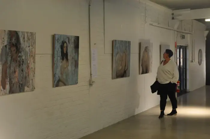 A visitor viewing paintings in the XCHC gallery space